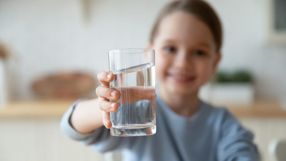 تصویر یک کودک شاداب و لیوان آب در دستش